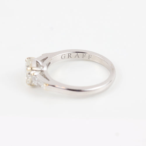 Bague Graff - Bague en or blanc 18 carats sertie d'un diamant central brillant et de diamants latéraux trapézoïdaux. 58 Facettes 130281
