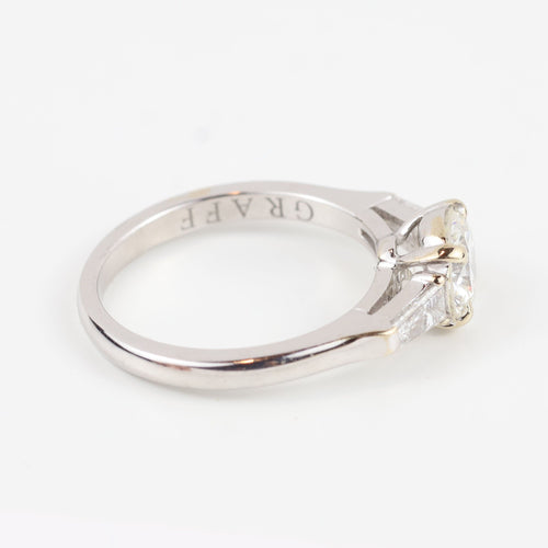 Bague Graff - Bague en or blanc 18 carats sertie d'un diamant central brillant et de diamants latéraux trapézoïdaux. 58 Facettes 130281